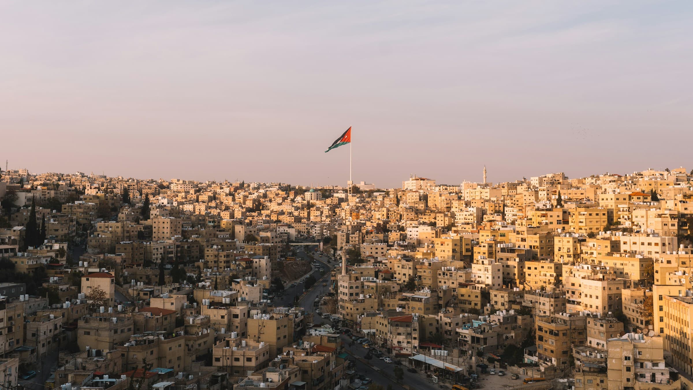 The Jordanian flag above the sunlit hills of Amman